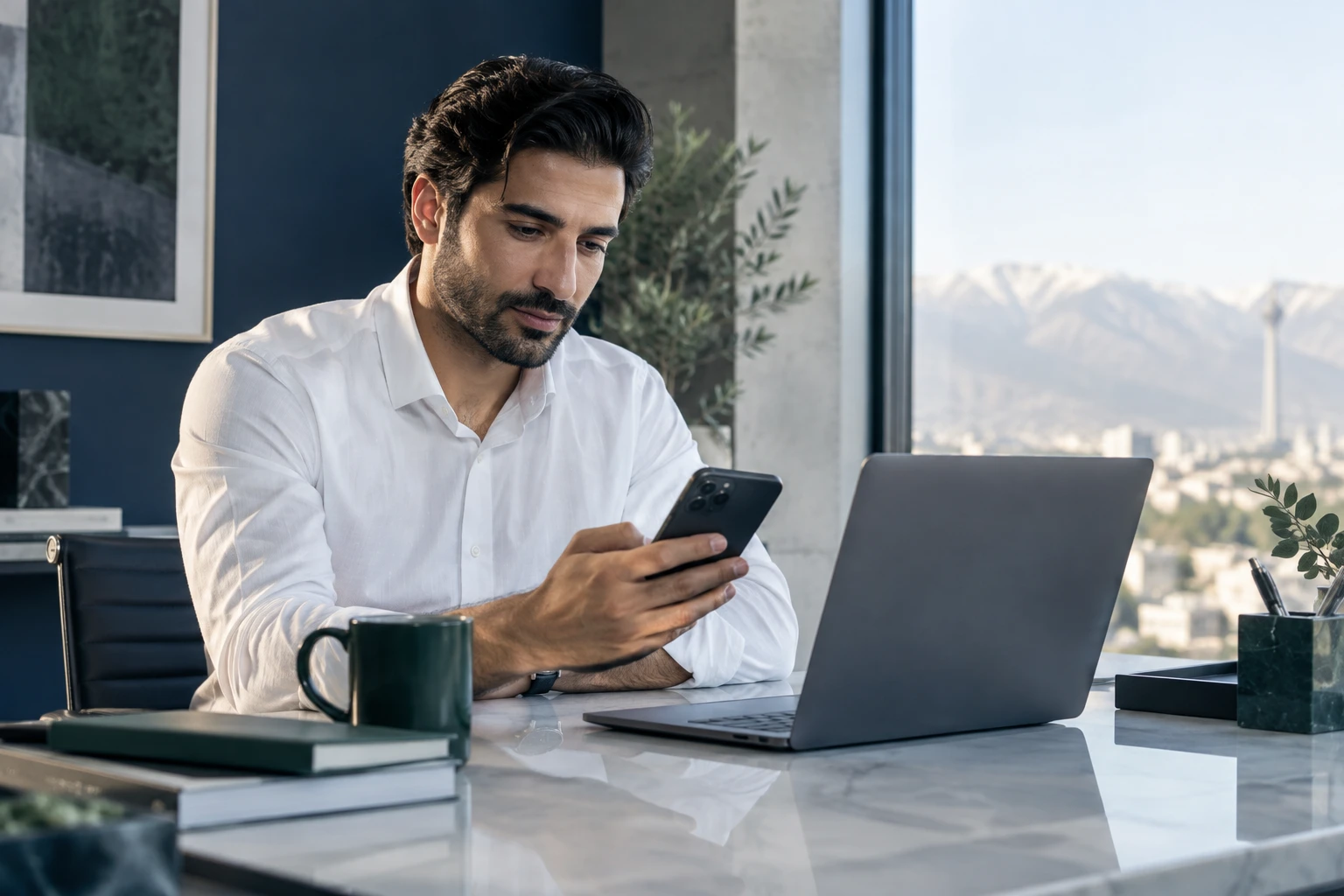 کارشناس سازمان در حال استفاده از موبایل کنار لپتاپ